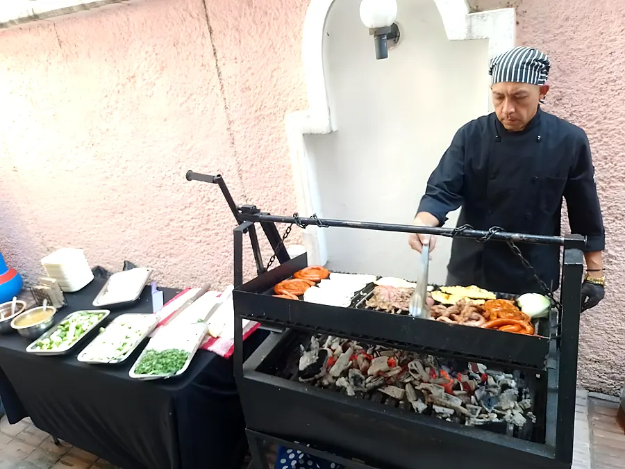 Cocinero en la parrilla junto a la mesa de salsas